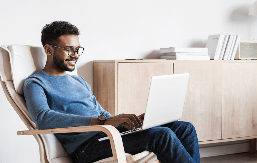 Man sitting in a chair with a laptop.